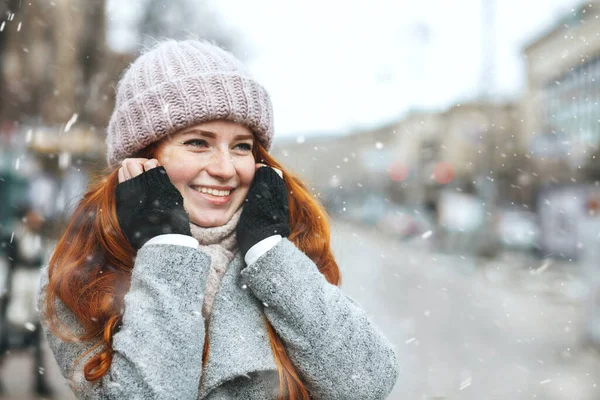 魅力的な赤い髪の女性は雪の中で街を歩くコートを着ています テキストのスペース — ストック写真