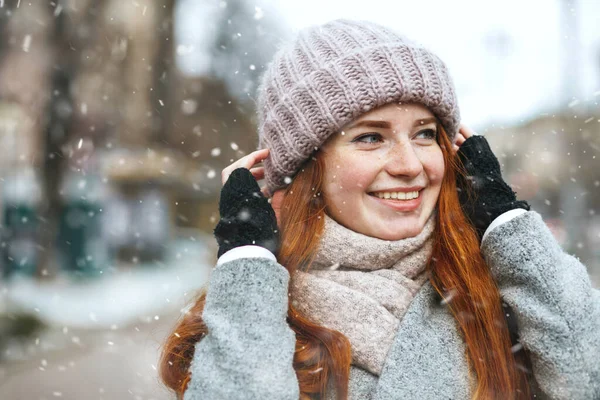エレガントな赤い髪の女性は 雪の中で街を歩くコートを着ています テキストのスペース — ストック写真