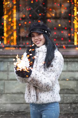 Kış tatillerinde parlak ışıklarla eğlenen sevimli genç bir kadın.