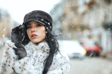 Göz kamaştırıcı genç kadın kış caddesinde çelenklerle süslenmiş bir şekilde yürürken ceket giyiyor. Metin için boşluk