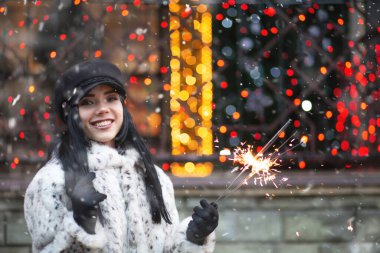 Parlak ışıklarla kış tatilinin tadını çıkaran büyüleyici genç bir kadın. Boş boşluk