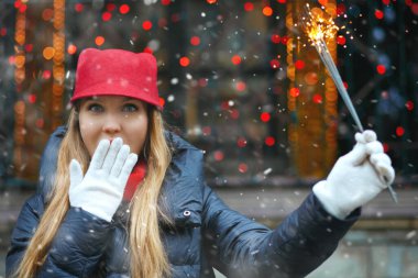 Şaşkın sarışın kadın tatil fuarında bengal ışıklarıyla oynayan kırmızı şapkalı. Metin için boşluk