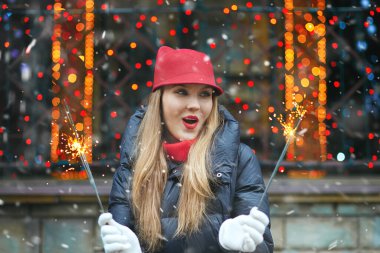 Güzel sarışın kadın, tatil fuarında bengal ışıklarıyla oynayan kırmızı şapkalı. Metin için boşluk