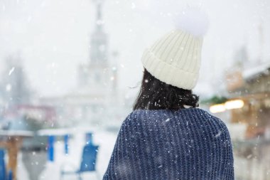 Genç kadın kar yağışı sırasında kış parkında yürürken beyaz şapka takıyor. Dikiz aynası. Boş boşluk