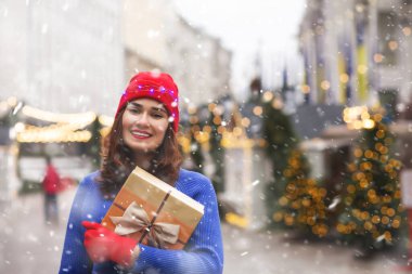 Kar yağışı sırasında bayram kış festivalinde hediye alan mutlu genç bayan. Metin için boşluk