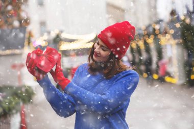 Noel fuarında elinde kurdeleyle hediye paketi tutan mutlu genç bir kadın. Boş boşluk