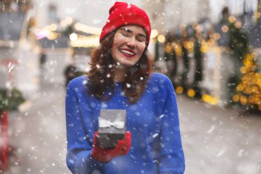 Noel fuarında hediye kutusunu kurdeleyle açan komik bir genç kadın. Boş boşluk