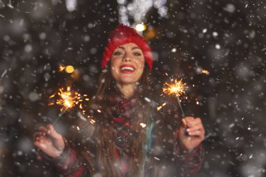 Çekici bir genç kadın kar yağarken sokakta maytaplarla oynuyor.