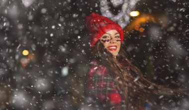 Klas, uzun saçlı bir kadın Noel panayırında karlı havanın tadını çıkarıyor.