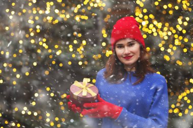 Noel fuarında elinde kurdeleyle hediye paketi tutan sevimli genç bir kadın. Boş boşluk