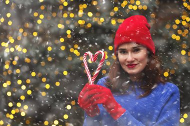 Güzel bir kadın Noel ağacında şeker tutarken kırmızı şapka takıyor. Boş boşluk