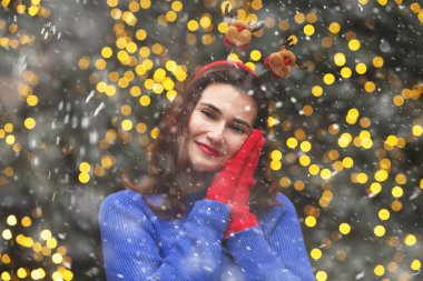 Güzel esmer kadın, kar yağarken Noel ağacında eğlenirken komik saç halkası takıyor. Boş boşluk