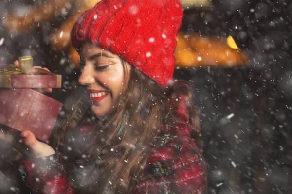 Cheerful Young Woman Receiving Gift Christmas Market Snowfall Space Text — Stock Photo, Image