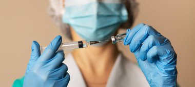 Kadın doktor lateks eldivenler ve tıbbi önlük ile doldurulan şırınga ile hastanede koronavirüs aşısı, yakın çekim