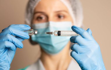 Kadın doktor şırıngayı covid 19 aşısıyla dolduruyor.