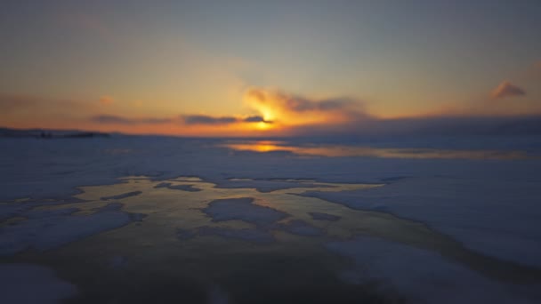 Ufukta turuncu bir alacakaranlık var. Kuzey manzarası. Donmuş gölde dramatik gün batımı. — Stok video