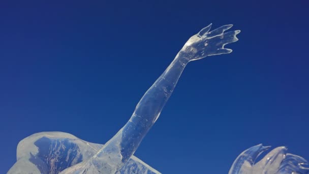 Escultura de hielo. La mano helada vidriosa alcanza el cielo azul. Obra traslúcida. — Vídeos de Stock