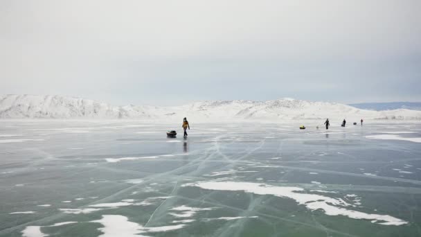 Touristengruppe mit ausgerüsteten Schlitten wandert über breiten gefrorenen Eissee. — Stockvideo