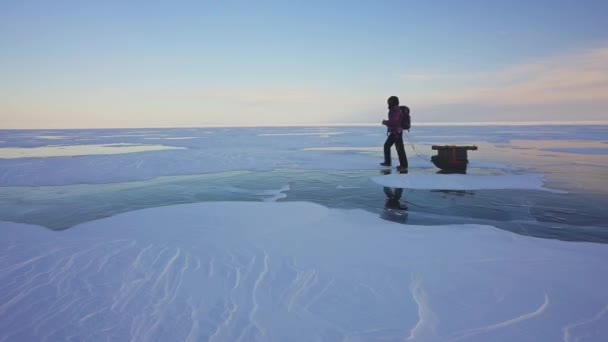 Omul care trage sania echipata peste gheata congelata. Drumeţii singur. Peisaj sever cu zăpadă — Videoclip de stoc