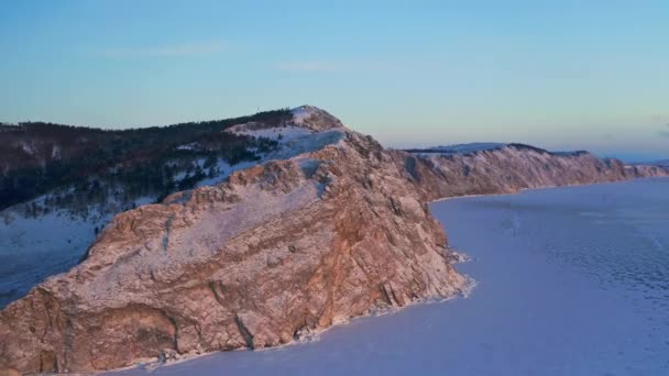 Panorama aéreo. Nevada montaña fría en rosa puesta de sol redondeada con hielo congelado lago — Vídeos de Stock