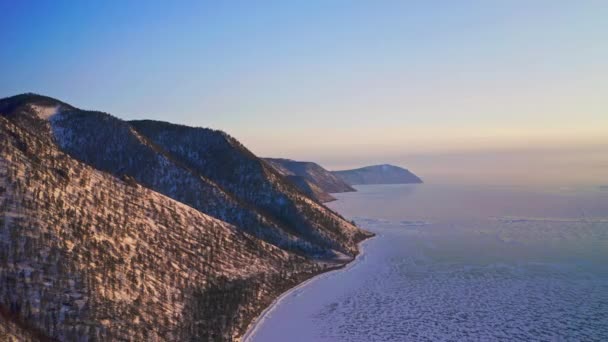 Zicht vanuit de lucht. Snowy bergketen naast bevroren ijsmeer op gouden uur — Stockvideo