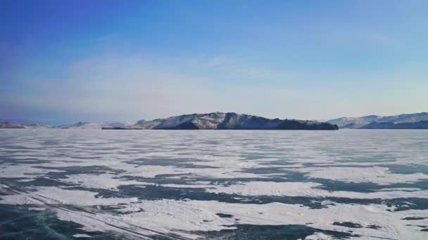 Vuelo aéreo sobre hielo congelado cubierto de nieve a cordillera cerca del horizonte — Vídeos de Stock
