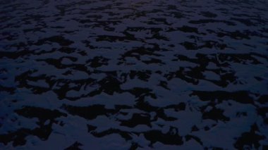  İnsansız hava aracı, koyu karlı donmuş buzdan ufkun üzerinde turuncu gün doğumuna doğru eğilir.