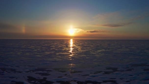 Luchtvlucht boven besneeuwd bevroren ijsmeer naar glorieuze heldere zonsondergang over horizon — Stockvideo