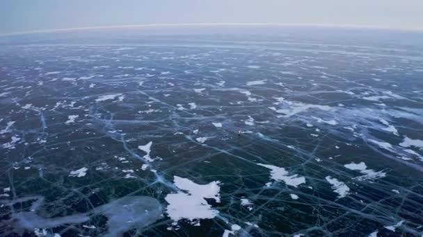 Panorama aereo. Un uomo solo che pattina sul lago ghiacciato. Motivo ghiaccio scuro incrinato — Video Stock