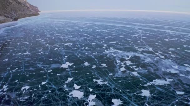 Niesamowita panorama z powietrza. Samotny człowiek jeżdżący po zamarzniętym ciemnym lodzie. Widok na ptaki — Wideo stockowe