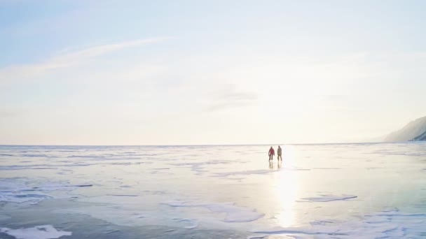 Bruslaři kloužou po hladkém, nekonečném zamrzlém jezeře. Přírodní kluziště ve zlaté hodině — Stock video