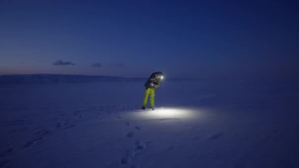 Hombre perforando el pozo de agua en la penumbra de la noche. Aburrido un agujero en hielo helado nevado — Vídeos de Stock