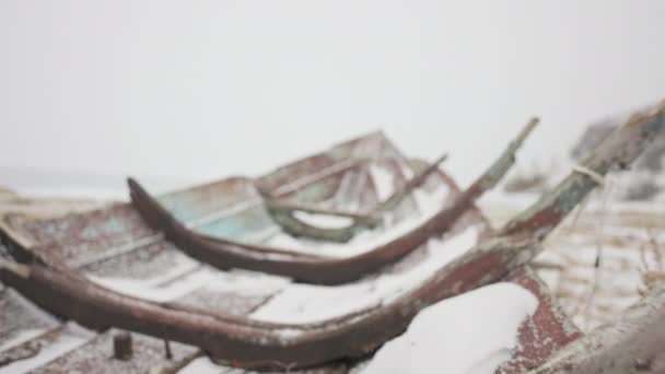 Stary drewniany, zaniedbany wrak łodzi pozostawiony na pustym wybrzeżu pod zimnym białym śniegiem — Wideo stockowe