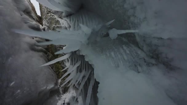 Scharfe weiße Eiszapfen hängen an der Decke in der Grotte. Gefrorene Stalaktiten — Stockvideo