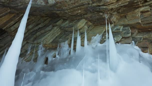 White sharp frozen icicles, stalagmites formed on floor at ice cave in huge rock — Stock Video