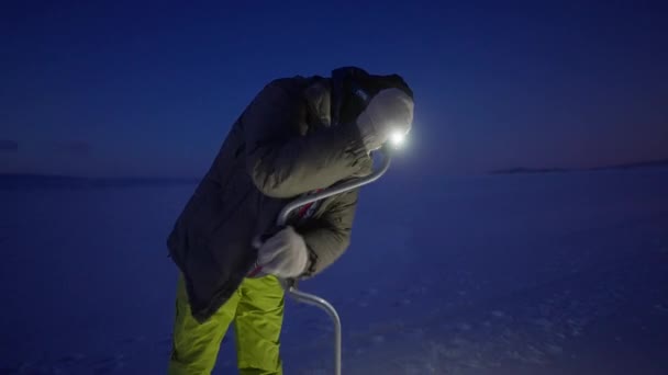 凍結湖で手オーガーと男ドリル穴。夜になると水がよくなる — ストック動画