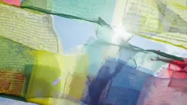 Colorful, yellow, green, red buddhist prayer flags flap in wind under blue sky — Stock Video
