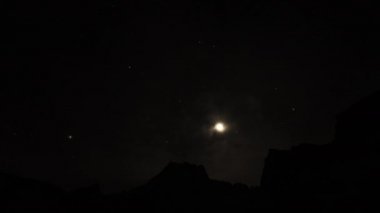 Harika bir zaman dilimi. Ay, kara karanlık dağ zirvesinin üzerine iniyor. Karanlık gece gökyüzü