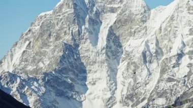 Büyük özgür kuş kar boyunca uçuyor. Kayalık dağlar mavi güneşli gökyüzünde zirve yapıyor.