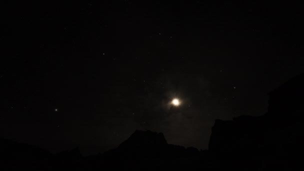 Дивовижний часовий пояс. Місяць спускається над гірською вершиною чорного кольору. Темне нічне небо — стокове відео