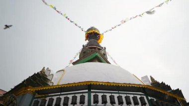 Dua bayraklarının çelenkleri Swayambhunath 'ın altın beyazı tepesinde asılı.