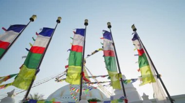 Beyaz şenlikli Swayambhunath stupasında bayrak direkleri üzerinde renkli dua bayrakları dalgalanıyor