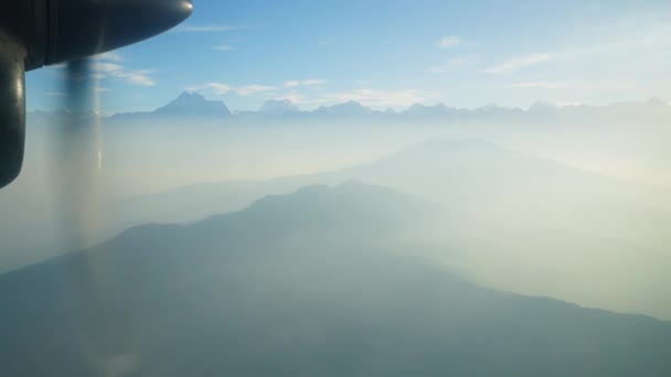 Vliegen boven Himalaya bergen in blauwe mist. Cirkel propeller buiten vliegtuig — Stockvideo