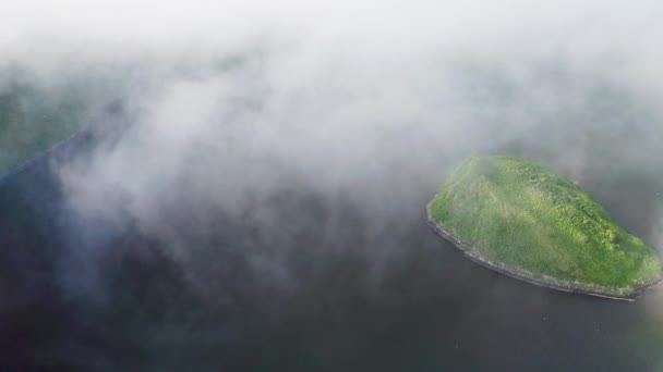 Panorama aéreo. Islote verde se esconden por densas nubes de niebla volando sobre el agua oscura — Vídeo de stock