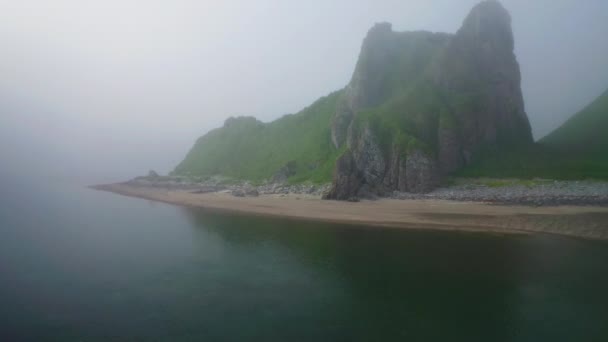 Panorama nebuloso. Voando acima do mar azul calmo para colinas verdes na praia de areia deserta — Vídeo de Stock