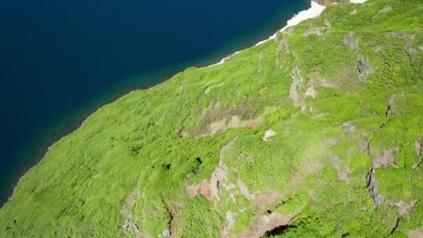 Дивовижний накладний політ безпілотника над незайманими зеленими пагорбами на бухті блакитної води Відеокліп