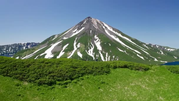 Чудовий вид з повітря. Людина на зеленому пагорбі. Сніговий вулкан, блакитна водяна лагуна Стоковий Відеоролик