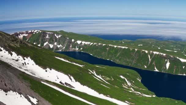 Vogels oog panorama. Sneeuwgroene vulkaanhellingen, blauwe waterlagune, mistige horizon — Stockvideo