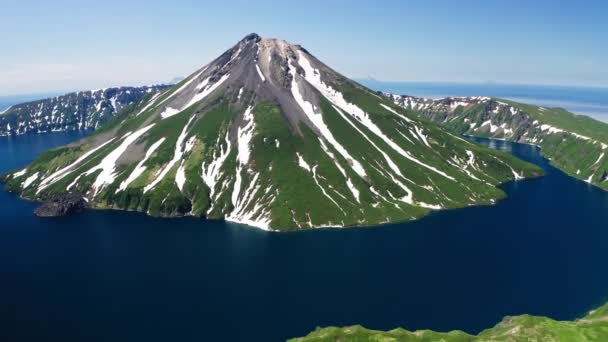 豪華な空中ビュー。雪の緑の火山の円錐形、青い水のカルデラの周り、晴れ ストック映像