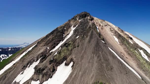 Panorama z powietrza. Snowy zielony szczyt wulkanu nad czystym błękitnym niebem w słońcu — Wideo stockowe